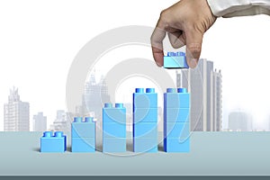 Hand holding blue block complete growth bar graph shape