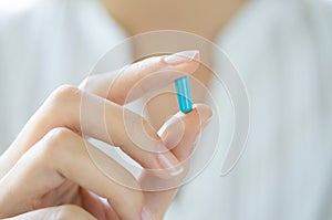 Hand holding blue capsule pill