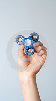 Hand Holding a Blue Fidget Spinner Toy for Relaxation on White Background