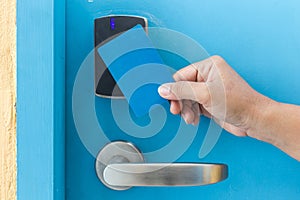 Hand holding blue hotel keycard in front of electric door