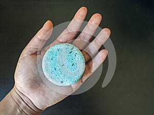 Hand holding a Blue Shampoo bar before use in the shower version 1