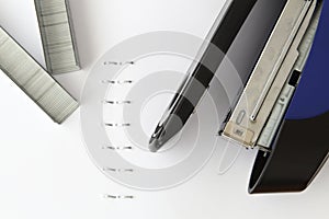 Hand holding blue stapler stapling papers