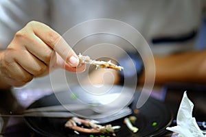 Hand holding bone of Roasted chicken leg, Bitten eaten deep fried crispy chicken wing in restaurant