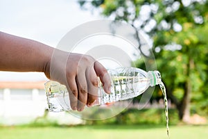 hand holding bottle pouring water on blurred green bokeh background