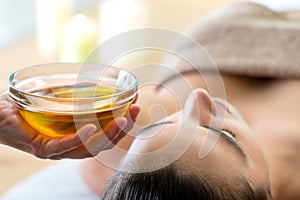 Hand holding bowl with aromatic oil in spa.