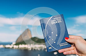 Hand holding Brazilian passport with SugarLoaf Mountain in Rio de Janeiro, Brazil in background