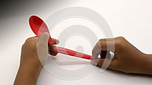 Hand holding a broken red plastic spoon