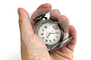 A hand holding a brown colored carved oriental pocket watch