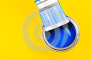 Hand holding Brush  on open can of paint on yellow background. Renovation concept - Image