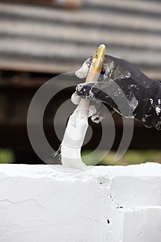 Hand holding brush painting white color to concrete fence wall