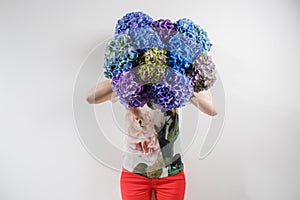 Hand holding a bunch blue color hydrangea white background. bright colors. purple cloud. 50 shades