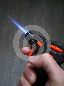Hand holding a Burning Kitchen blowtorch