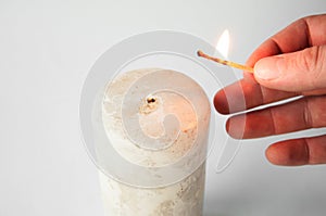 Hand holding a burning match and lights a candle
