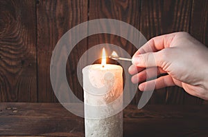 Hand holding a burning match and lights a candle