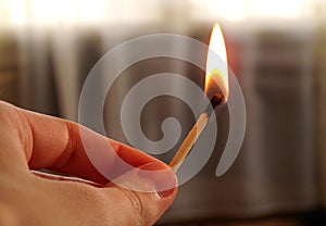 Hand holding a burning match. Match with fire and flame on a dark background. The concept of arson and fire. A burning match in hi