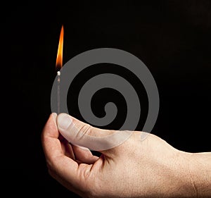 Hand holding burning match stick