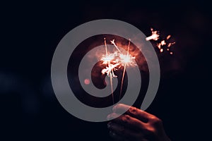 Hand holding burning Sparkler blast on a black bokeh background