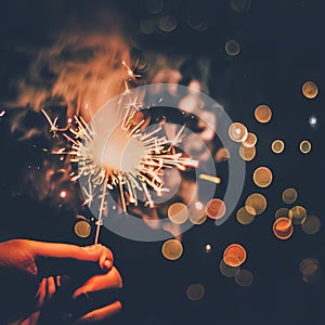 Hand holding burning Sparkler blast on a black bokeh background at night,holiday celebration event party,dark vintage tone