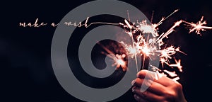 Hand holding burning Sparkler blast with make a wish word on a b