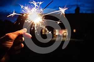 Hand holding a burning sparkler at blue hour