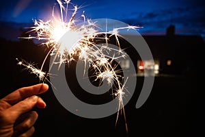 Hand holding a burning sparkler at blue hour