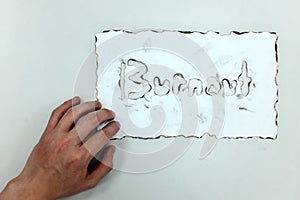 Hand holding a burnt white paper with burnout word. Work life balance, work stress and burnout concept