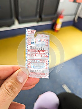A hand holding a bus ticket in bus.