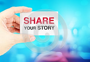Hand holding Business card with share your story with blur blue