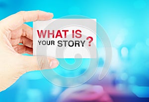 Hand holding Business card with What is your story? with blur bl