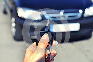 Hand holding button on the remote car. In selective focus of woman hand presses on the remote control car alarm systems.