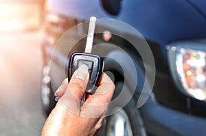 Hand holding button on the remote car. In selective focus of woman hand presses on the remote control car alarm systems.