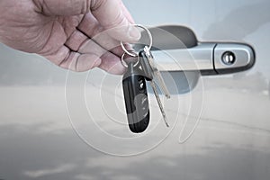 Hand Holding Car Keys in front of Car Door
