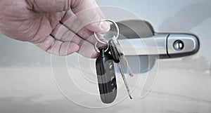 Hand Holding Car Keys in front of Car Door