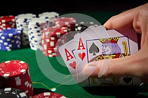 hand holding cards at poker table with chips stacked
