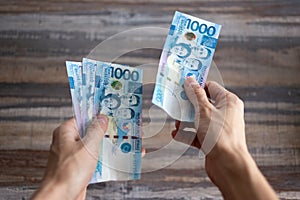 Hand holding cash banknote of one thousand Philippines peso paying bills, payment procedure or bribe, salary