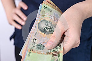 Hand holding cash banknote of  Vietnamese dong VND paying bills, payment procedure or bribe, salary