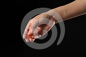 Hand holding cayenne pepper on black background