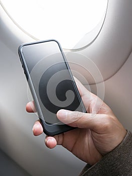 Hand holding cell phone on airplane