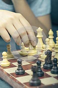 Hand holding chess figure while playing chess at home. Education, strategic board game, leisure, entertainment at home