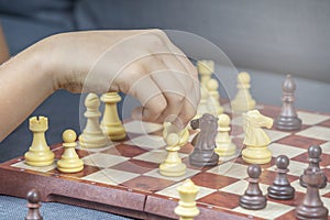 Hand holding chess figure while playing chess at home. Education, strategic board game, leisure, entertainment at home