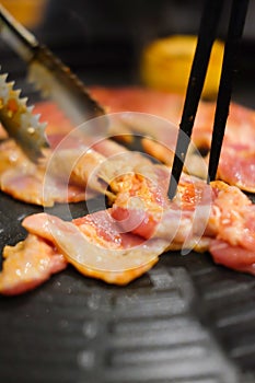 Hand holding chopstick with grilled korean pork