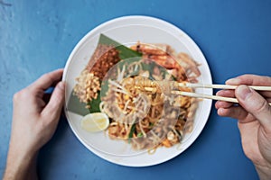 Hand holding chopsticks with Pad Thai food