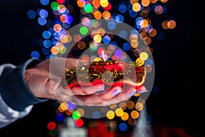 Hand holding a Christmas candle decoration against colorful bokeh lights background
