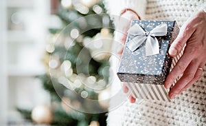 hand holding Christmas gift box in front of holiday lights