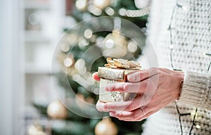 hand holding Christmas gift box in front of holiday lights