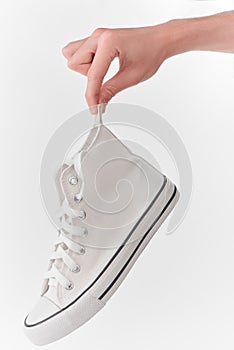 Hand holding a clean white canvas sneaker