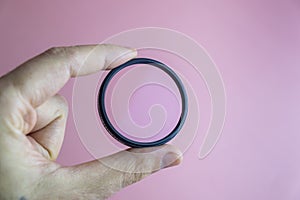hand holding clear camera filter isolated on pink