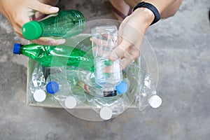 Hand  holding clear and green recyclable plastic bottle putting in paper garbage bin for recycling. waste management and plastic