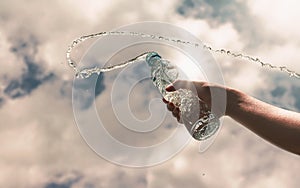 Hand holding a clear plastic bottle of pure drinking water refreshing and splash on a hot background with a hungry and thirsty