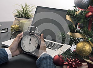 Hand holding clock midnight for Christmas day in the office.